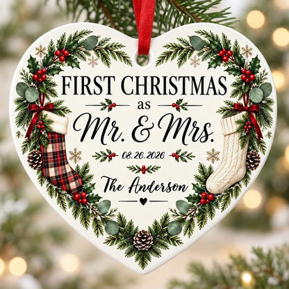 Heart ornament with greenery border, two stockings on bows, and 'FIRST CHRISTMAS as Mr. & Mrs.' text.