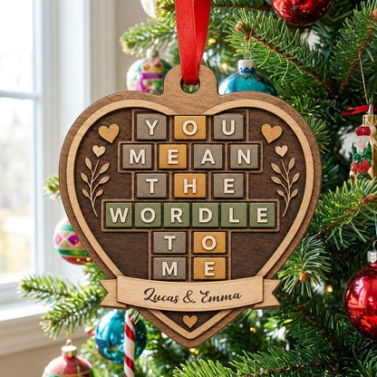 Heart-shaped wood ornament with Wordle-style tiles reading You Mean The Wordle To Me and names on a bottom banner.