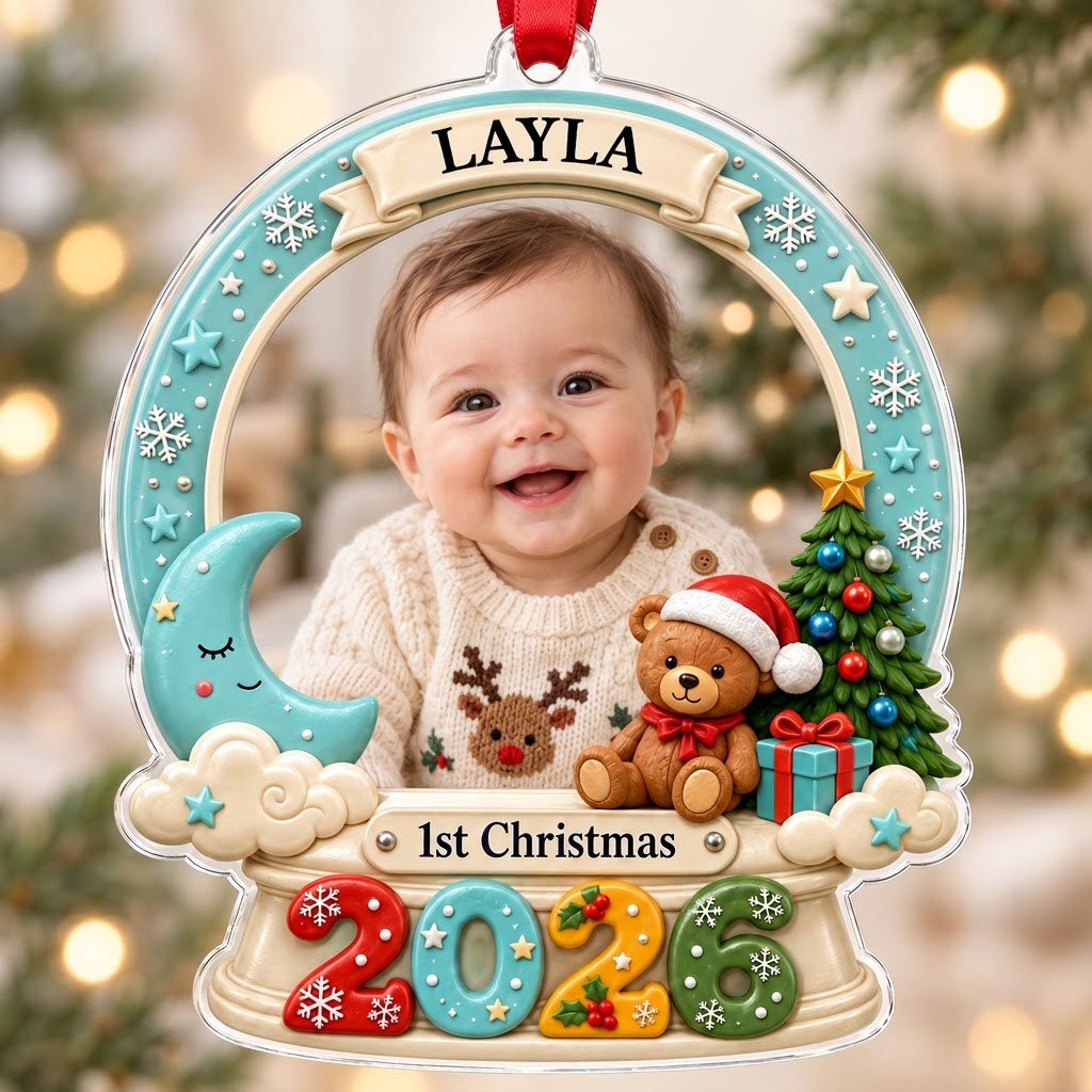 Acrylic snow-globe ornament with baby photo, "1st Christmas", teddy bear, moon, clouds, and big 2026 at the base.
