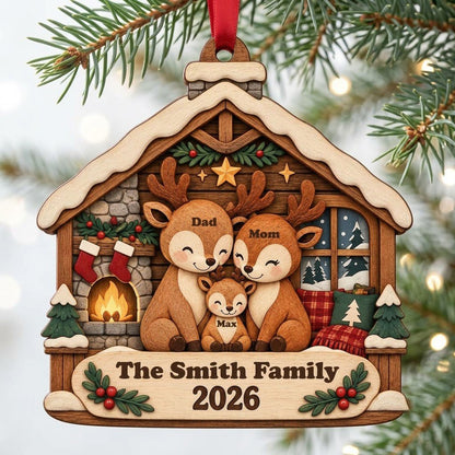 House-shaped wood ornament with deer family by a fireplace and snowy window, personalized with names and year.