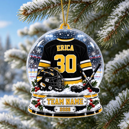 Acrylic snow globe ornament with hockey jersey, helmet, crossed sticks, puck, holly, and a silver plaque base.