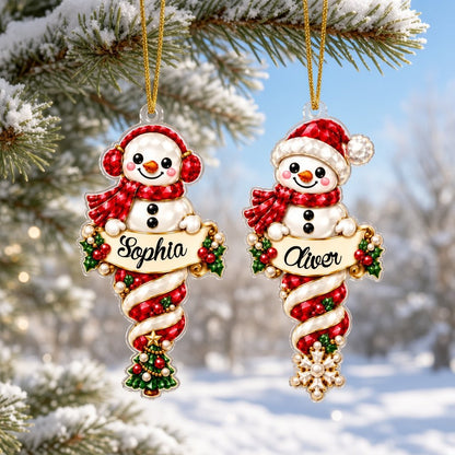 Custom-cut acrylic snowman ornaments with red scarves and scroll banners personalized with a child's name.