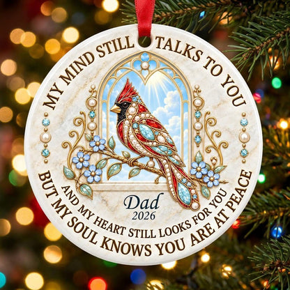 Round ceramic ornament with a red cardinal by a gold arched window, blue flowers, pearls, and a faux marble border.