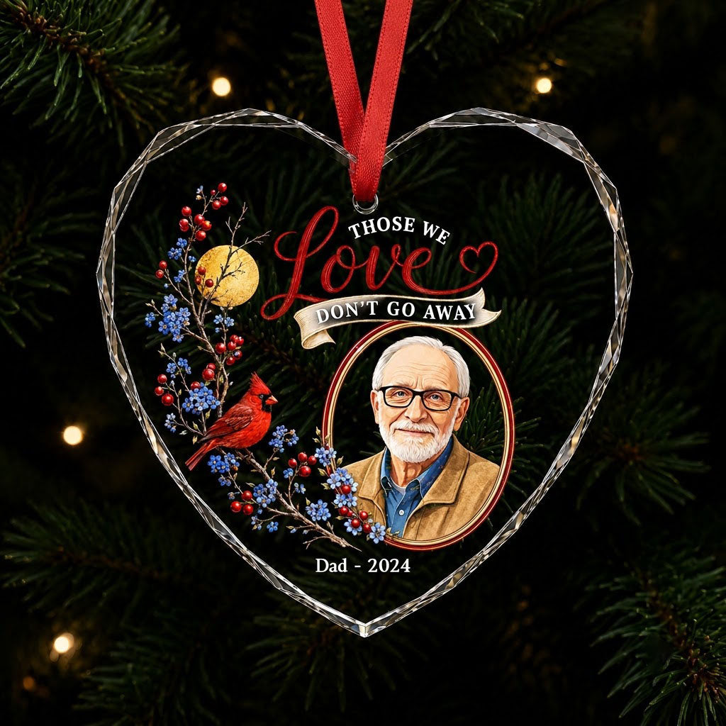 Heart-shaped glass ornament with a red cardinal, golden moon, photo frame and the quote 'THOSE WE Love DON'T GO AWAY'.