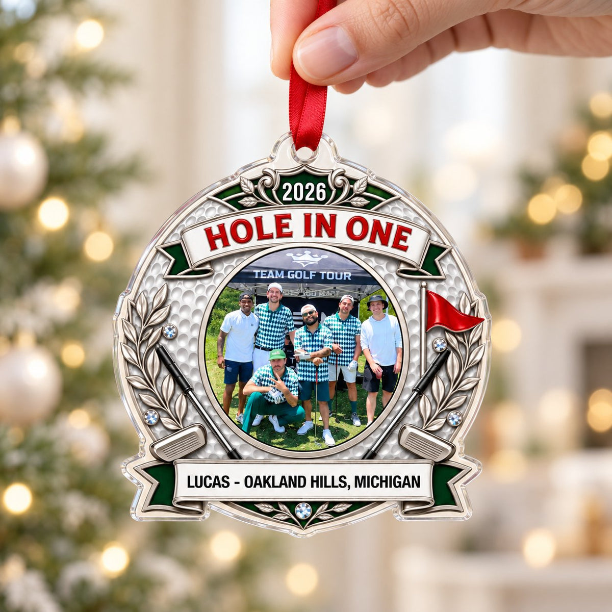Silver trophy-style golf ornament with laurel branches, crossed clubs, red flag, 2026 and HOLE IN ONE, plus a circular p