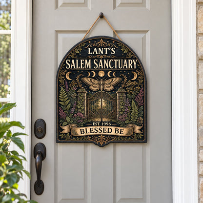 Arch-shaped wooden sign with death's-head hawkmoth, moon phases, wrought-iron gate and ivy on a black background.