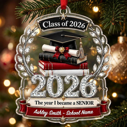 Acrylic ornament shows Class of 2026 text, cap, diploma, jeweled laurel wreath and banners personalized with name and sc