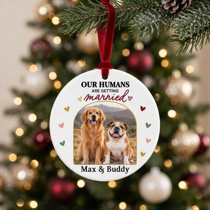 Round ceramic ornament with arch dog photo, “OUR HUMANS ARE GETTING married” text, and colorful heart accents.