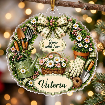 Scalloped acrylic ornament with a floral gardening wreath, tools, and "Grow with Love" plus a personalized name.