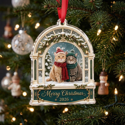 Arched window acrylic ornament with pine garland, gold bells, two cats in winter hats and scarves, and a green banner fo