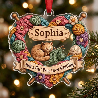 Heart-shaped acrylic ornament with yarn wreath, knitting needles, brown cat and "Just a Girl Who Loves Knitting" text.