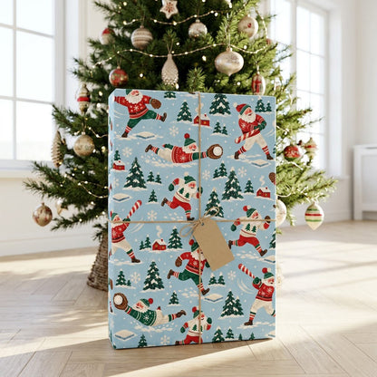 Light blue wrapping paper with Santa playing baseball, pine trees, small red houses, bases, and snowflakes in a repeatin