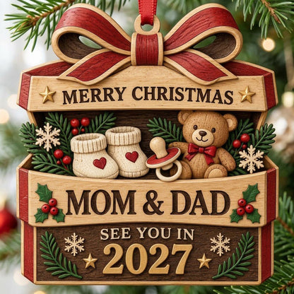 Gift box-shaped wood ornament with red bow, baby booties, teddy bear, and 'Mom & Dad See You In 2027' text.