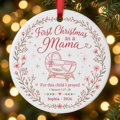 Round ceramic ornament with pink floral wreath, baby bassinet line art, stars, and First Christmas as a Mama.