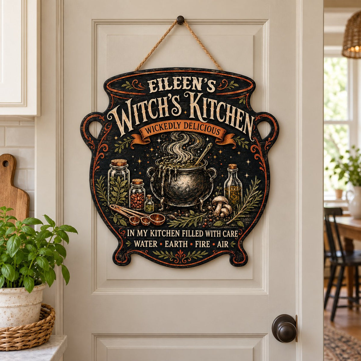 Custom-cut wooden sign shaped like a cauldron with herbs, potion jars, orange scroll and Witch's Kitchen text.