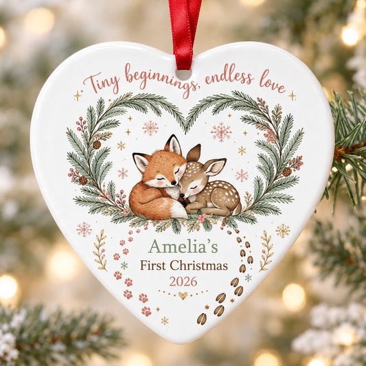 Heart ceramic ornament with sleeping baby fox and fawn in an evergreen wreath with berries and snowflakes.