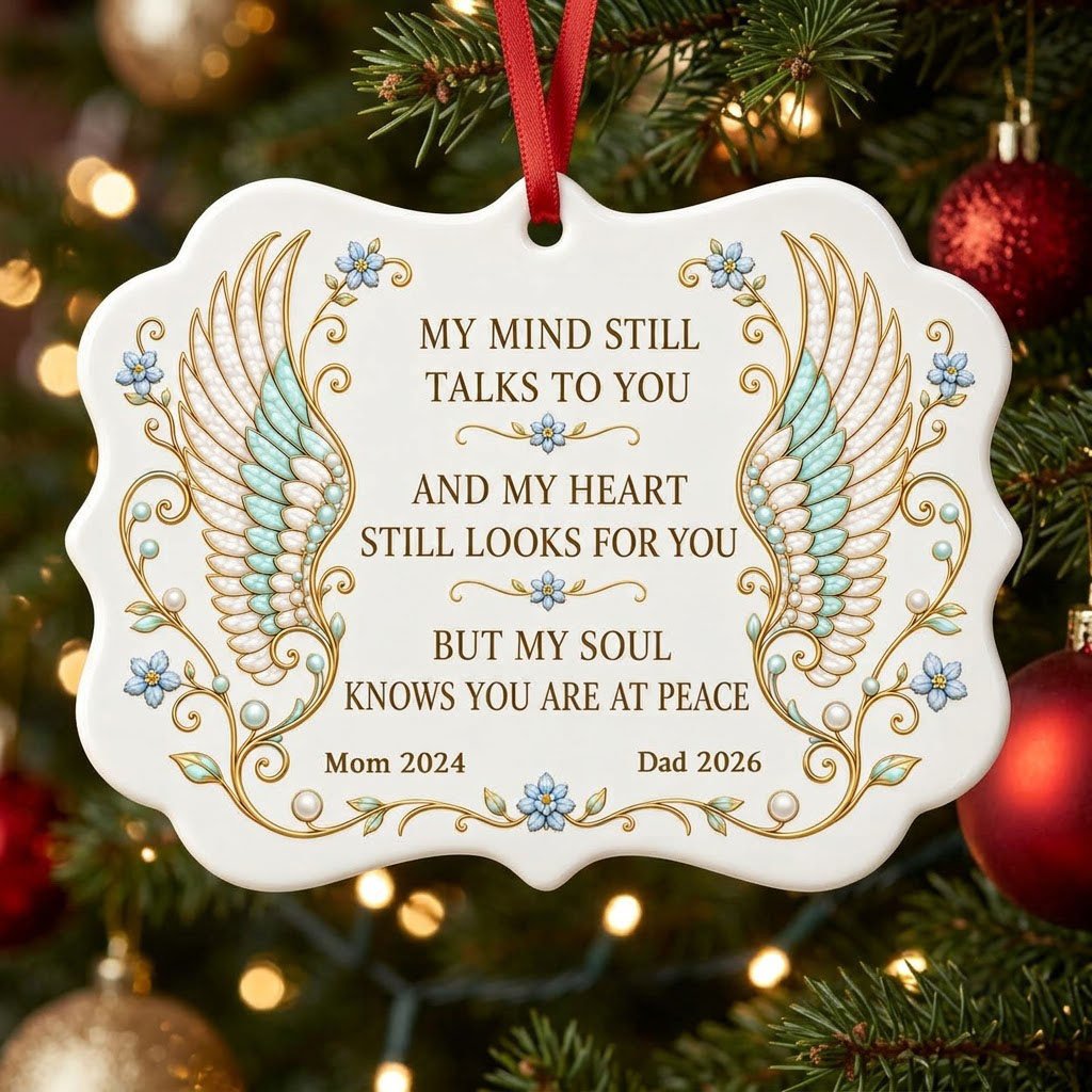 Medallion ceramic ornament with gold-outlined angel wings, blue forget-me-nots, and a memorial quote with name and year.