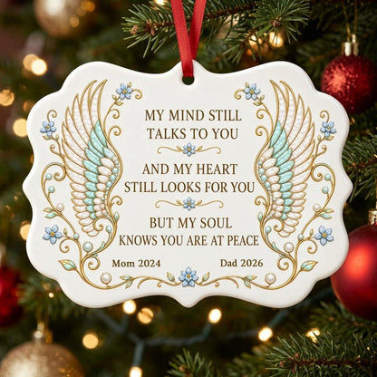 Medallion ceramic ornament with gold-outlined angel wings, blue forget-me-nots, and a memorial quote with name and year.