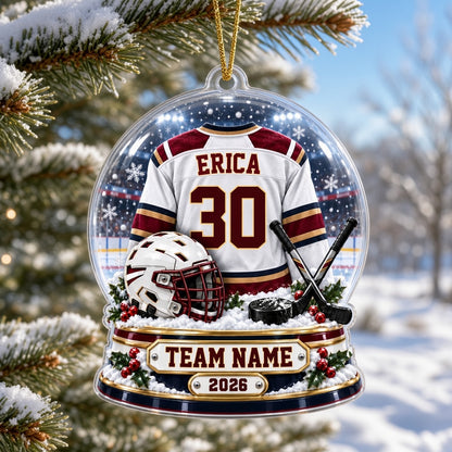 Acrylic snow globe ornament with hockey jersey, helmet, crossed sticks, puck, snowflakes and holly accents.