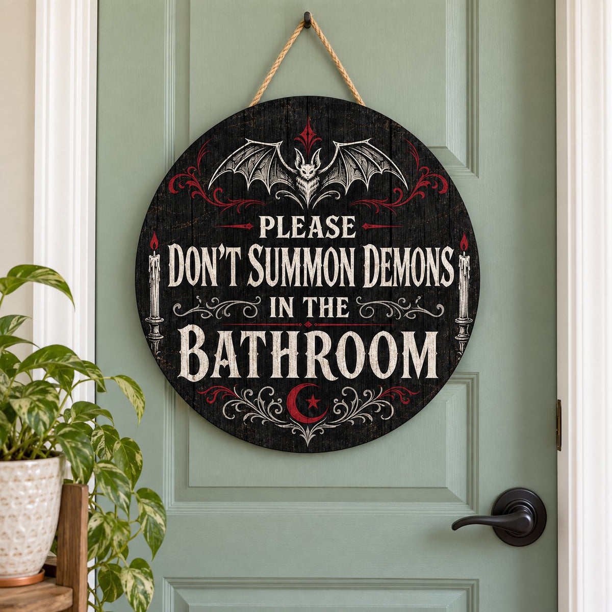 Round wooden sign with bat, filigree, candles and a crescent moon reading PLEASE DON'T SUMMON DEMONS IN THE BATHROOM.