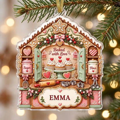 Custom-cut acrylic ornament shaped like a gingerbread house with baking tools, cupcakes, and a name banner.