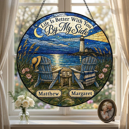 Round stained glass–style suncatcher with two blue Adirondack chairs by water and a lighthouse at night.