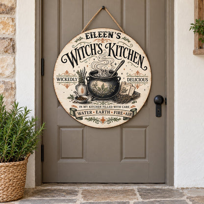 Round wooden hanging sign with a bubbling cauldron, herbs, spellbook, stars and the words Witch's Kitchen.