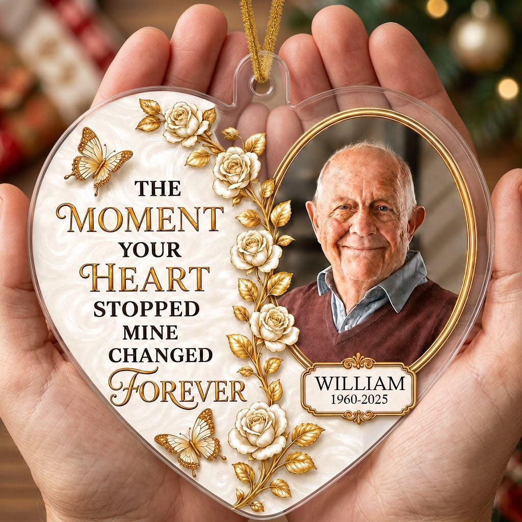 Heart-shaped acrylic ornament with a photo in a gold oval frame, white roses, gold butterflies, and a name plaque.