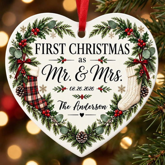 Heart ornament with greenery border, two stockings on bows, and 'FIRST CHRISTMAS as Mr. & Mrs.' text.