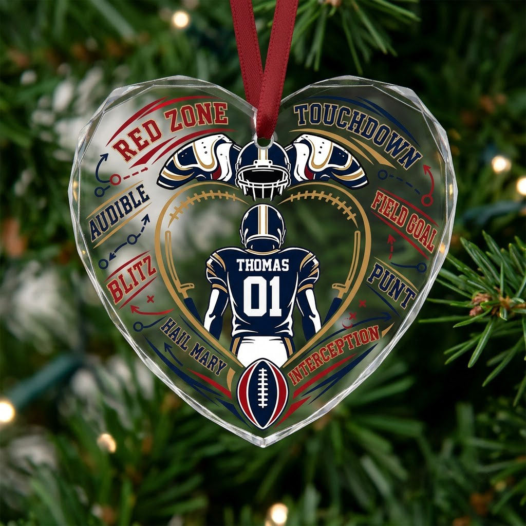 Heart-shaped glass ornament with back-view football player, gold stitched heart frame, football, and play diagram elemen