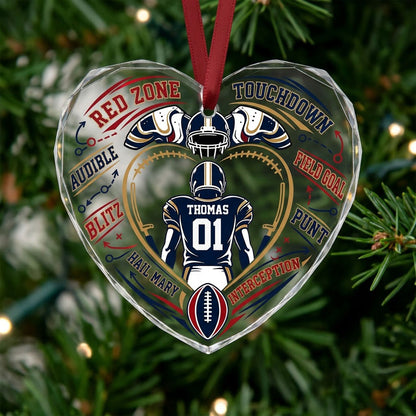 Heart-shaped glass ornament with back-view football player, gold stitched heart frame, football, and play diagram elemen