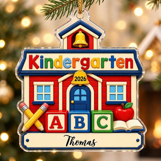 Red schoolhouse acrylic ornament with Kindergarten 2026, ABC blocks, pencils, apple, and a name on a white banner.