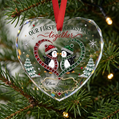 Heart-shaped stained glass suncatcher with two penguins in red and green scarves, jeweled trees, and silver snowflakes