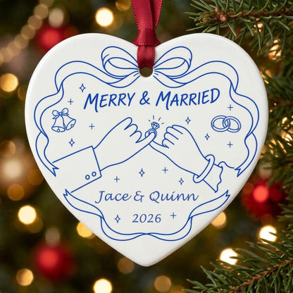 White heart ceramic ornament with blue line art: pinky promise hands, bells, rings, and MERRY & MARRIED text.