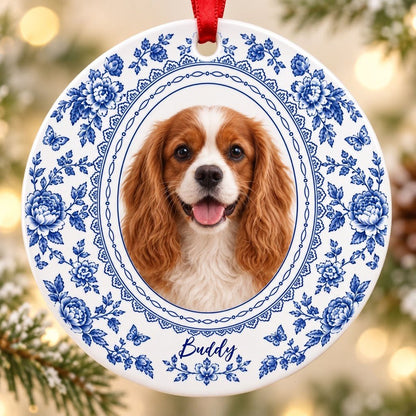 Round white ceramic ornament with blue Delft floral and butterfly pattern around an oval dog photo and name.