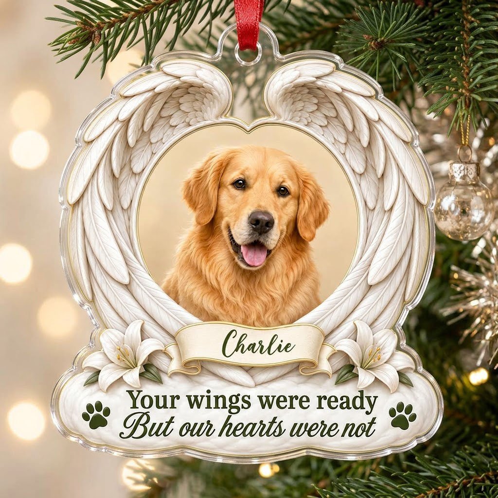 Clear acrylic angel wings ornament with a circular dog photo, white lilies, a dark green paw print, and a name banner.