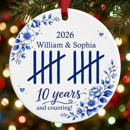 White round ceramic ornament with blue florals, tally marks, and 'years and counting!' plus names and year
