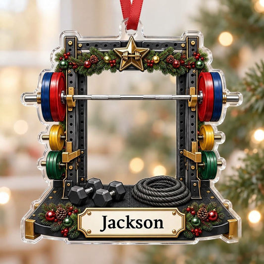 A squat rack-shaped acrylic ornament with garland, barbell, dumbbells, and a photo cutout above a name plaque.