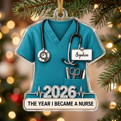 Teal scrub top acrylic ornament with stethoscope, ID badge, pocket tools, EKG line, 2026 numerals and a white name banne