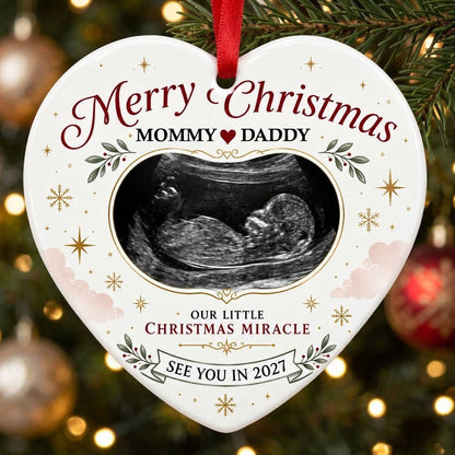 Heart ceramic ornament with ultrasound photo, gold starbursts, green leaves with red berries, and a bottom banner.