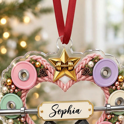 Clear acrylic heart ornament with pink rope wreath, pastel plates, barbell, crossed dumbbells, and a name plaque.