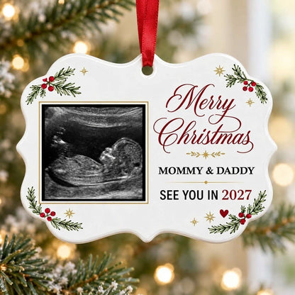 Round ceramic ornament with ultrasound photo, pine branches with red berries, gold starbursts and a red heart icon.