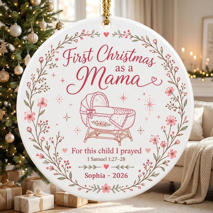 Round ceramic ornament with pink floral wreath, baby bassinet line art, stars, and First Christmas as a Mama.