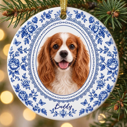Round white ceramic ornament with blue Delft floral and butterfly pattern around an oval dog photo and name.