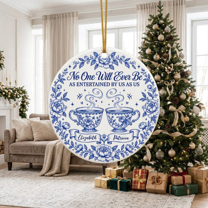Round white ceramic ornament with blue floral border and two teacups, personalized with two names