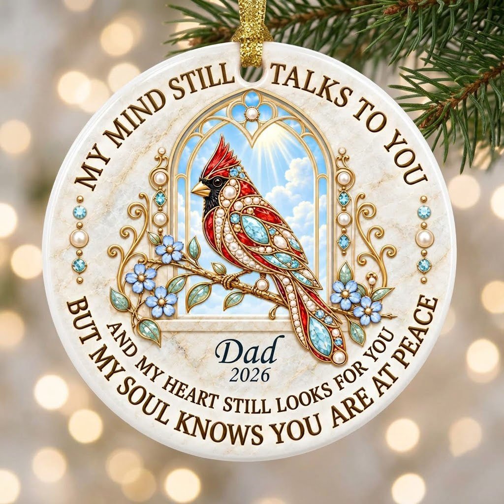 Round ceramic ornament with a red cardinal by a gold arched window, blue flowers, pearls, and a faux marble border.