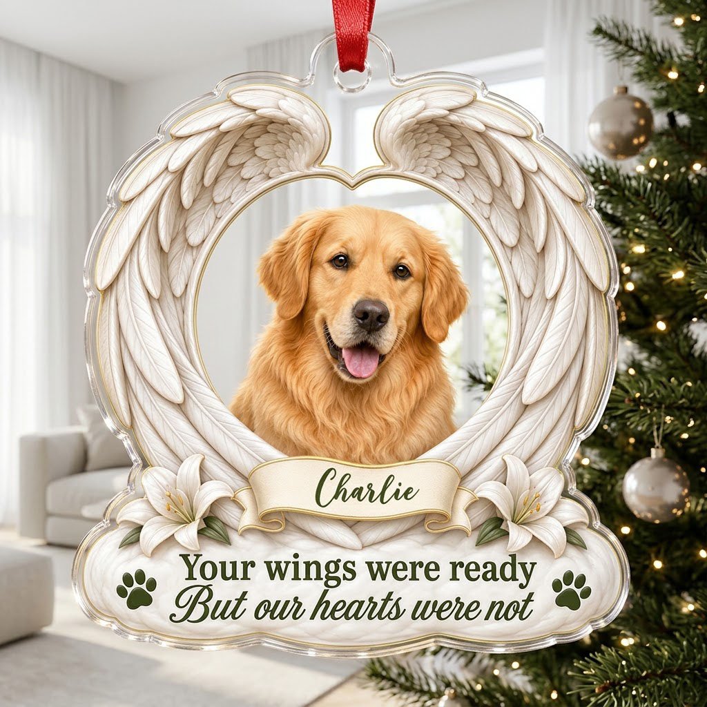 Clear acrylic angel wings ornament with a circular dog photo, white lilies, a dark green paw print, and a name banner.