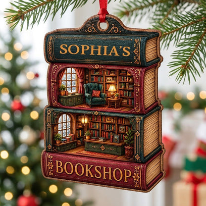 Custom-cut ornament of stacked books showing cozy bookshop rooms, BOOKSHOP text, and a personalized name.