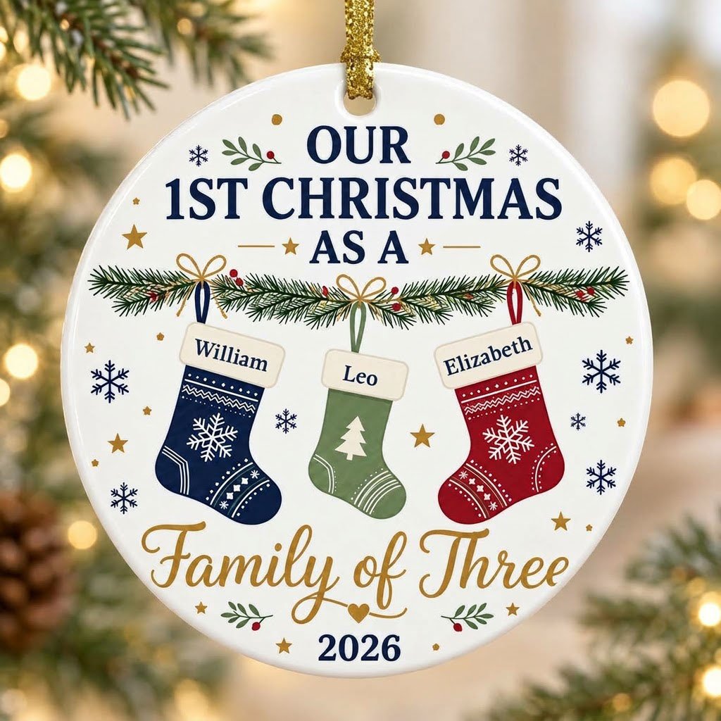 Round white ceramic ornament with garland, three stockings, and 'OUR 1ST CHRISTMAS AS A Family of Three 2026' text with 