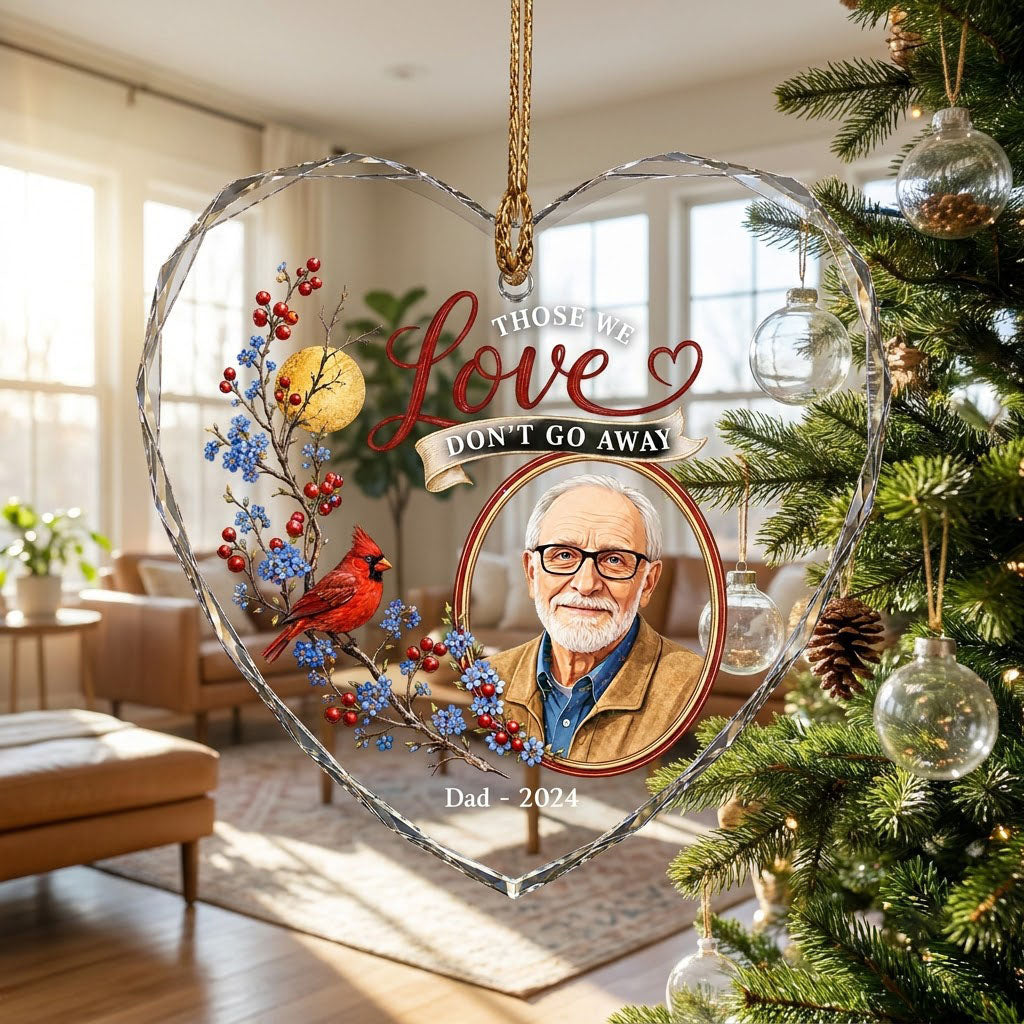 Heart-shaped glass ornament with a red cardinal, golden moon, photo frame and the quote 'THOSE WE Love DON'T GO AWAY'.